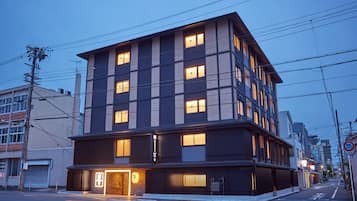 A modern multi-story building with illuminated windows, a ground-floor entrance, and a visible sign indicating a business establishment.