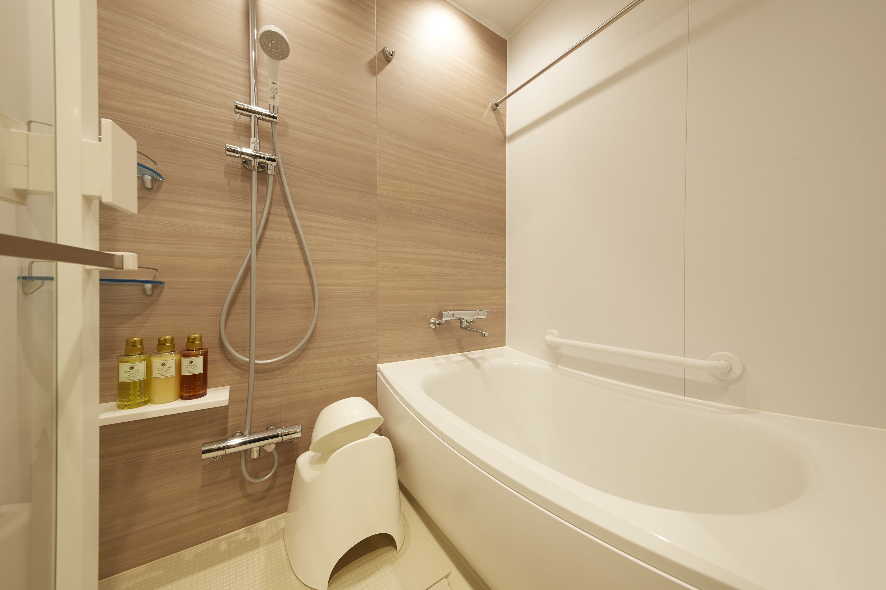Une salle de bain moderne avec une grande baignoire, une douche et des toilettes. On y trouve des étagères remplies de produits de toilette.