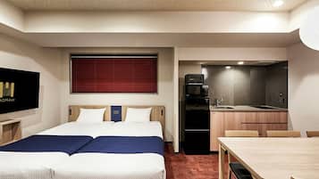A hotel room with a bed, a TV, a kitchenette, and a dining area.