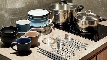 A kitchen counter with various utensils, bowls, and pots.