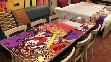 A hotel room with a colorful table, a sofa, and a bed.