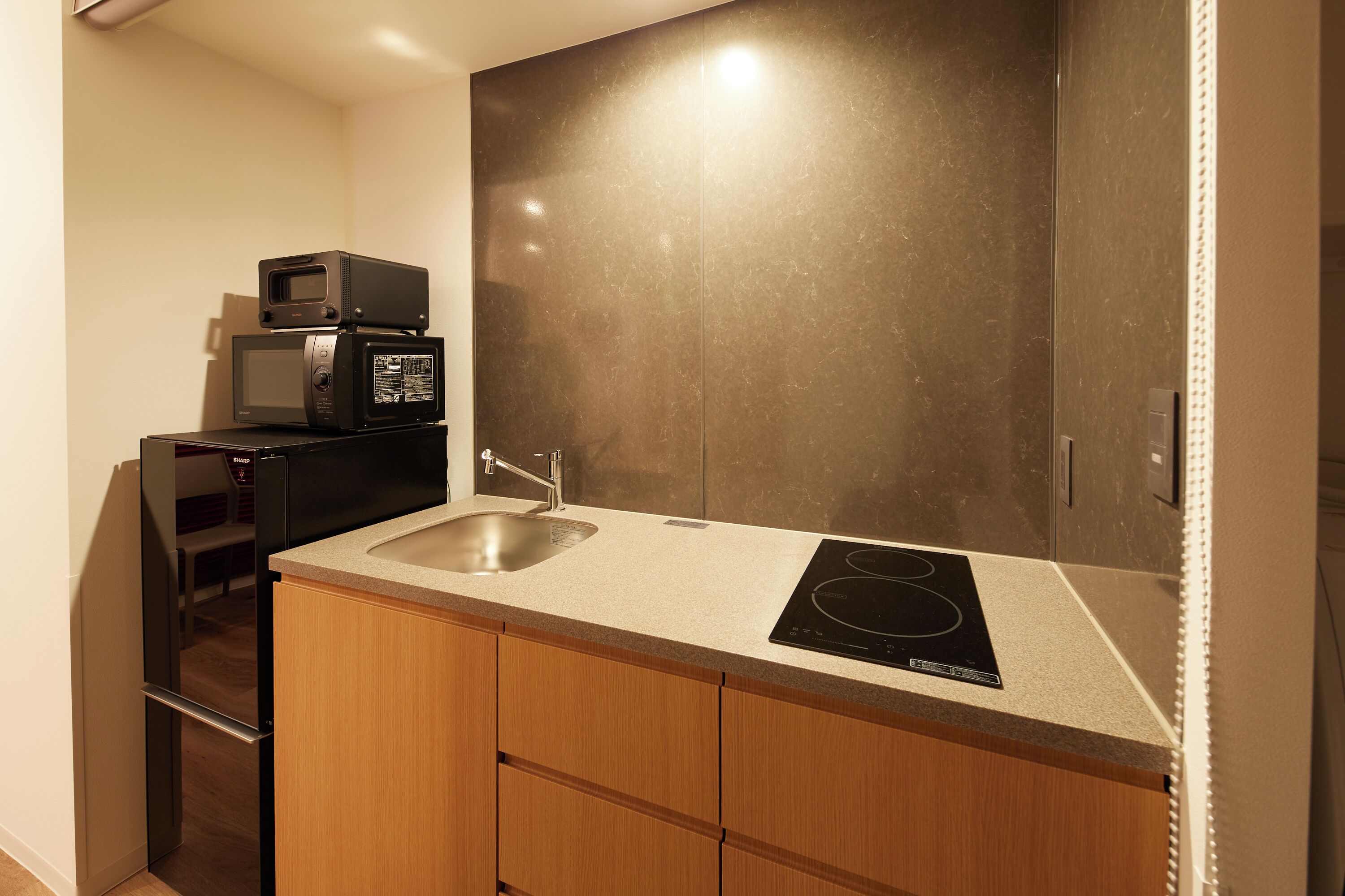 A compact kitchen with a sink, a microwave, and a built-in induction cooktop.