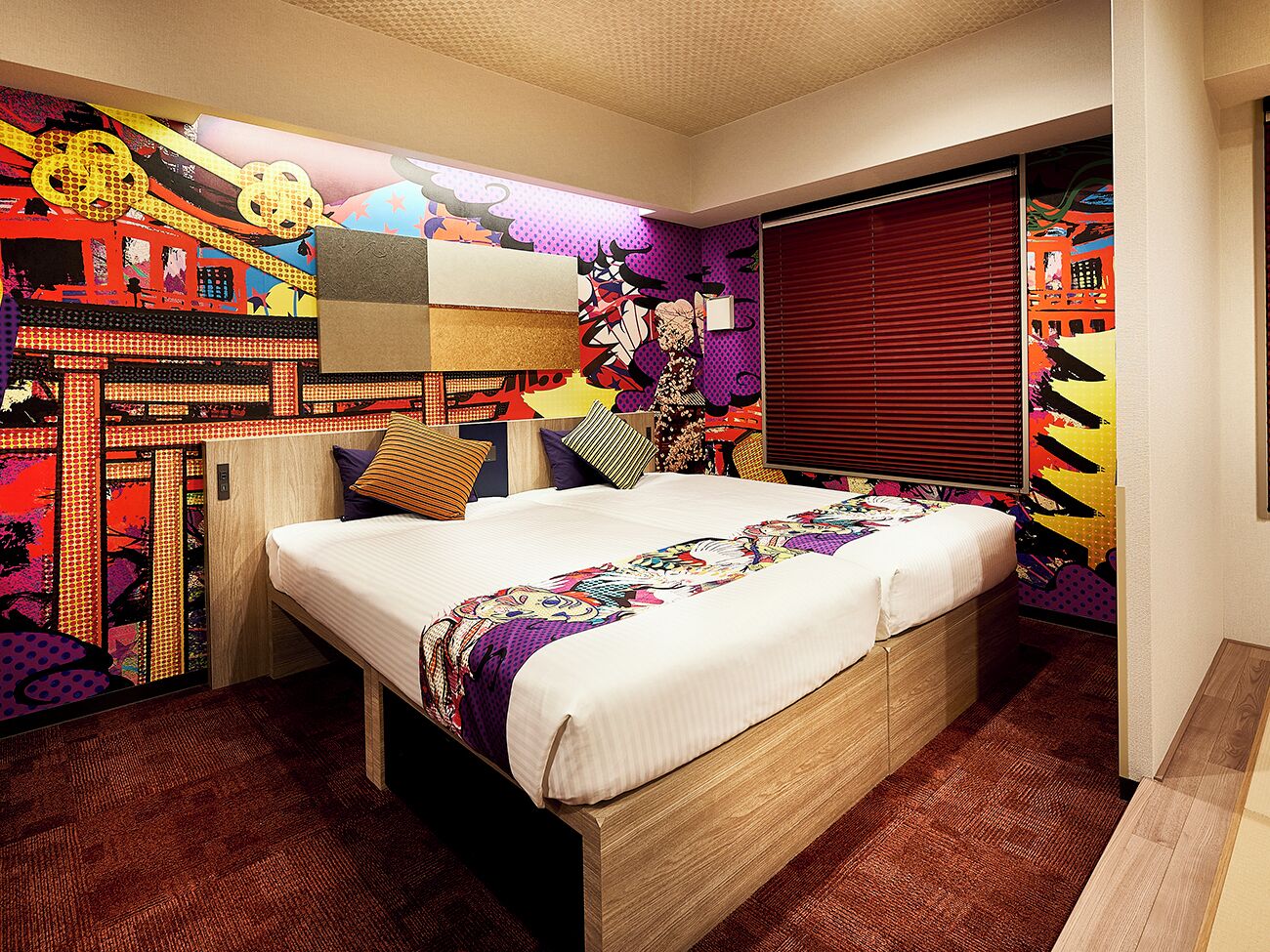 Un dormitorio con una cama grande, arte decorativo de colores y un ventanal con persianas.