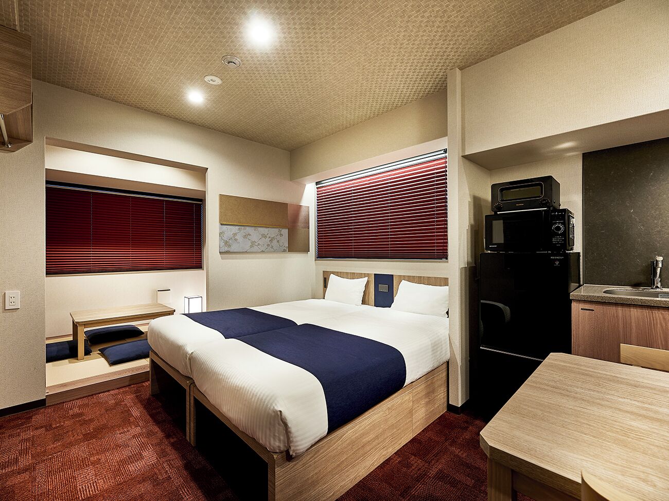 A hotel room with a bed, a desk, a microwave, and a refrigerator.