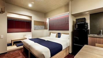 Una habitación de hotel con cama, escritorio, microondas y refrigerador.