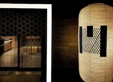 A modern building with a geometric metal gate and a cylindrical structure with a patterned design.
