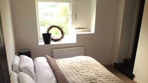 A bedroom with a bed, a window with a wreath, a radiator, and a black object on the floor.