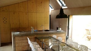 A modern kitchen with wooden cabinetry, a central island, and a dining area with a glass table and white chairs.