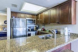 A kitchen with granite countertops, stainless steel appliances, and wooden cabinets. - Waterfront Views, Walk to Everything Pool, Pool (Sarasota)