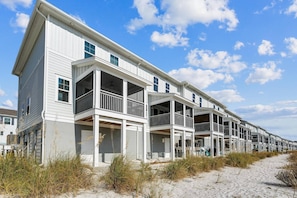 A row of coastal buildings with balconies, situated on a sandy beach.