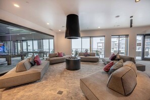 A modern living room with sofas, a coffee table, and a large black pendant light.