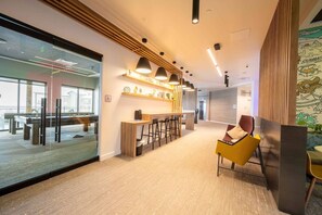 A modern office space with a bar area, seating, and a glass partition.