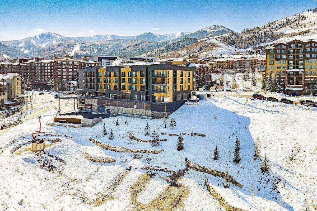 A modern hotel with multiple floors, a central courtyard, and a view of snow-covered mountains.