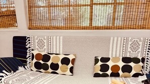Ein gemütliches Wohnzimmer mit einer Couch, verziert mit gemusterten Kissen, einem Couchtisch mit Holzbausteinen, die Wörter bilden, und einer dekorativen Pflanze als Mittelpunkt.