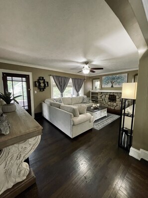 A spacious living room with a white sofa, a stone fireplace, and a ceiling fan. - Upstairs Unit with Office Space near Downtown Cleveland + National Park (Cleveland)
