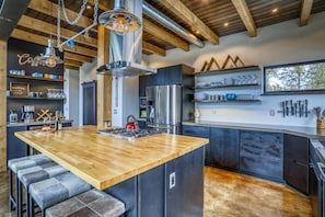 A modern kitchen with a central island, stainless steel appliances, and wooden accents.
