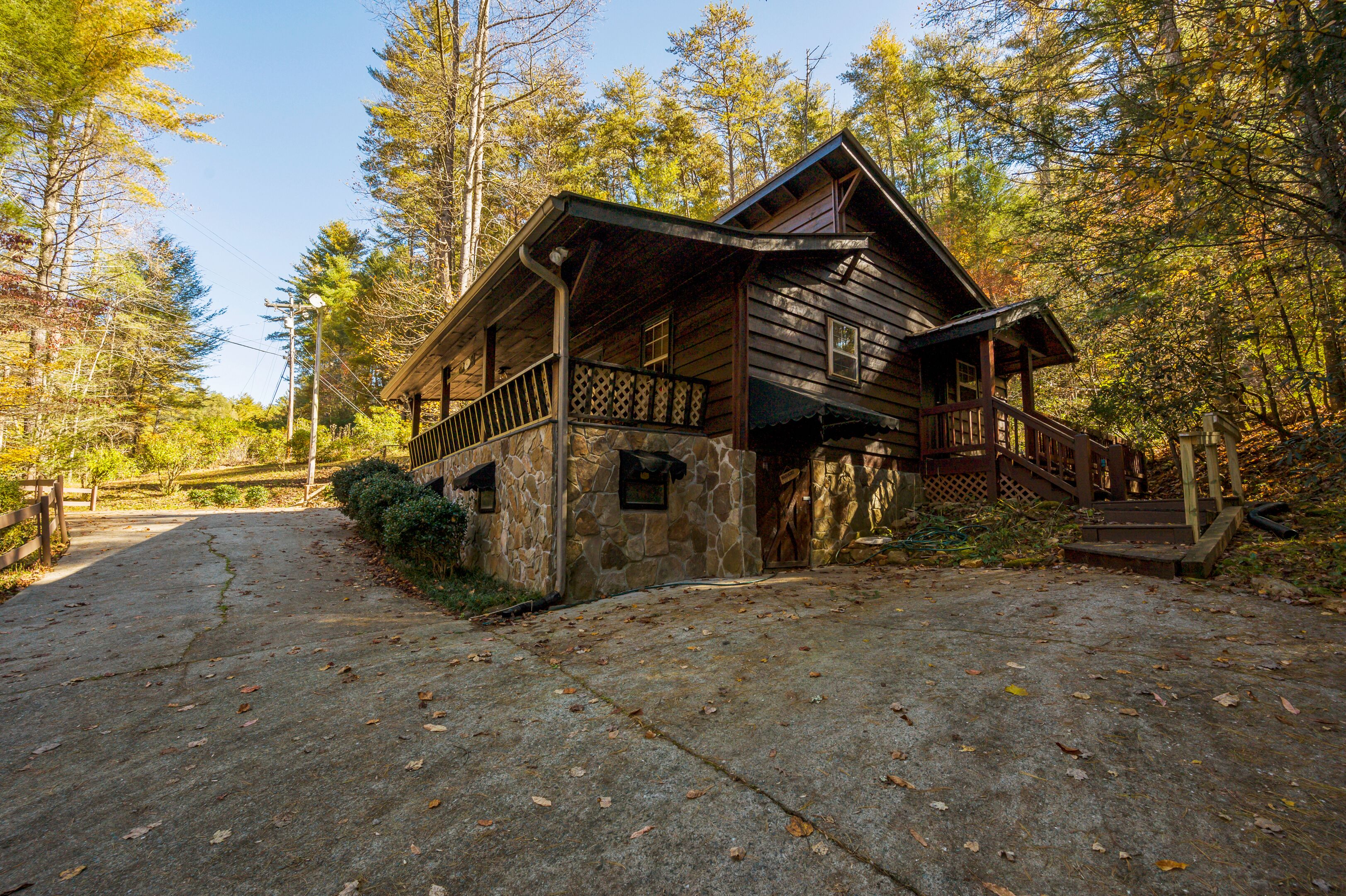 Een chalet met een stenen fundering, houten gevel en een veranda met een leuning.