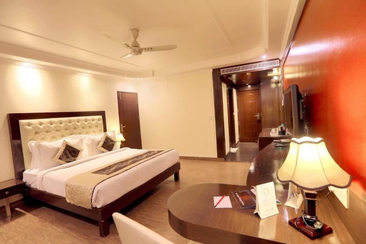 A hotel room with a bed, a desk, a lamp, and a ceiling fan.