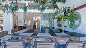 Un comedor con una isla central, sillas con cojines azules y una pared divisoria de vidrio.