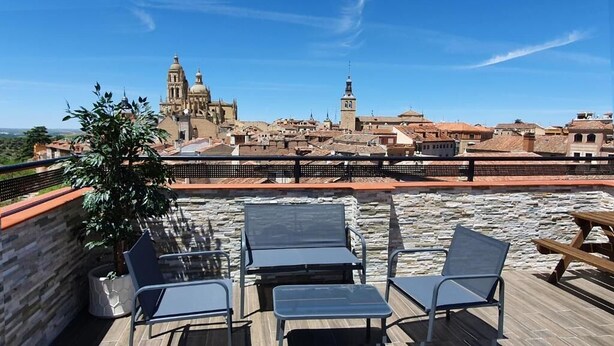 Une terrasse sur le toit, dotée d’un espace extérieur aménagé et offrant une vue sur des bâtiments historiques.
