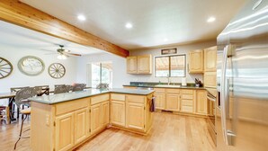 Une cuisine spacieuse avec des meubles en bois, un grand îlot central et un réfrigérateur en acier inoxydable.