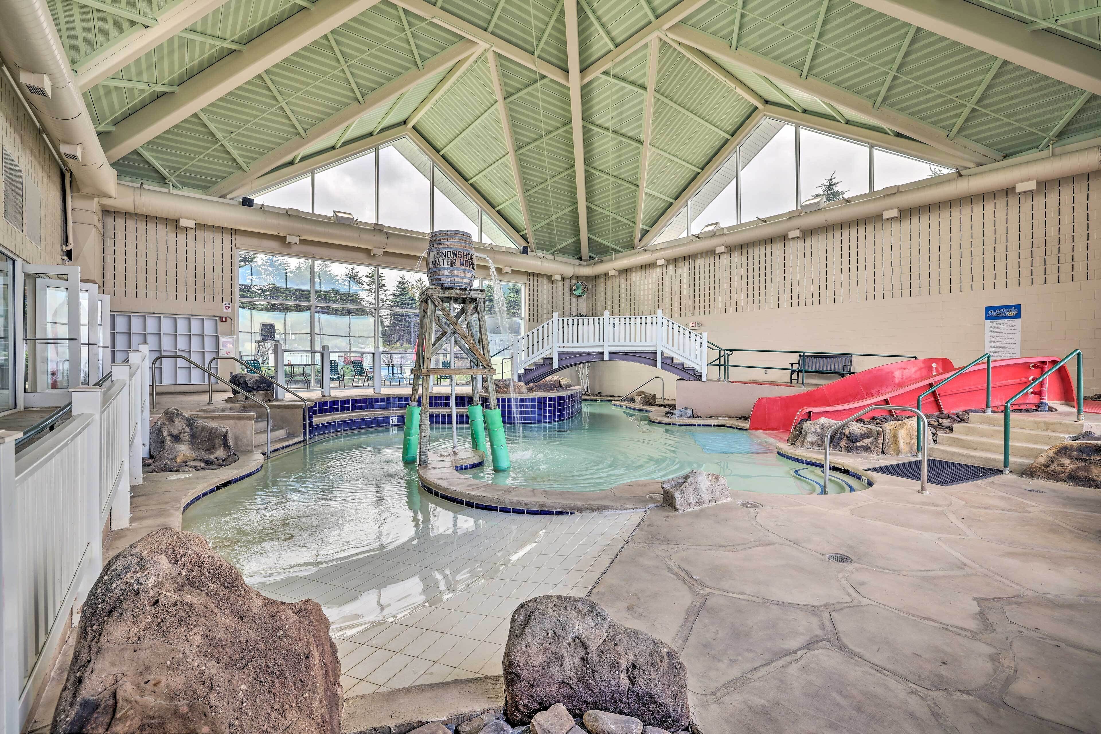 An indoor swimming pool with a water slide, a lifeguard tower, and a covered roof structure.