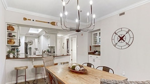 A dining area with a wooden table, bar stools, and a chandelier. - `Lakeside Haven`- Hot Tub, Pool, Lake view! (Lago Vista)