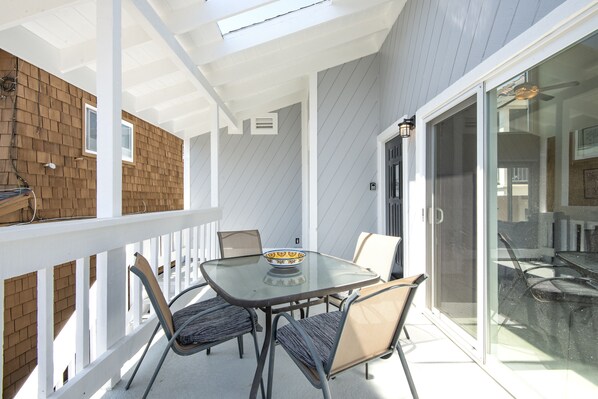 A covered patio with a glass table and chairs, a brick wall, and a sliding glass door leading to an outdoor area. - 2 Bedroom upper unit at our Oceanfront Home Newport Beach, California, United States (Newport Beach)