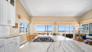 A spacious kitchen with a large marble island, wooden chairs, and a view of the ocean. - 5 Bedrooms on the Boardwalk w/4 Car Garage/Firepit (Newport Beach)