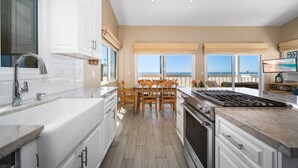 A modern kitchen with a large island, white cabinetry, and a view of the beach. - 5 Bedrooms on the Boardwalk w/4 Car Garage/Firepit (Newport Beach)
