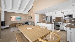 Une cuisine moderne avec des meubles blancs, des appareils en acier inoxydable et une table à manger en bois.