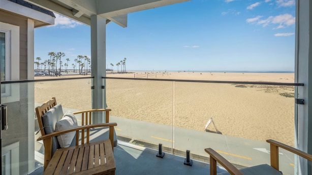 Un balcon donnant sur une plage de sable et des palmiers.