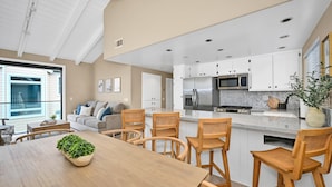 Una cocina moderna con armarios blancos, electrodomésticos de acero inoxidable y una mesa de comedor de madera con sillas.