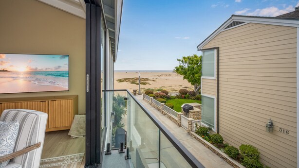 Un balcón con vista a la playa, un cuadro y una silla.