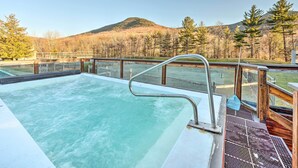 A hot tub with a wooden deck and metal railing, overlooking a mountainous landscape. - Lincoln Retreat w/ Village of Loon Amenity Access (Lincoln)