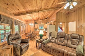 A wooden cabin interior with a living room, dining area, and kitchen.