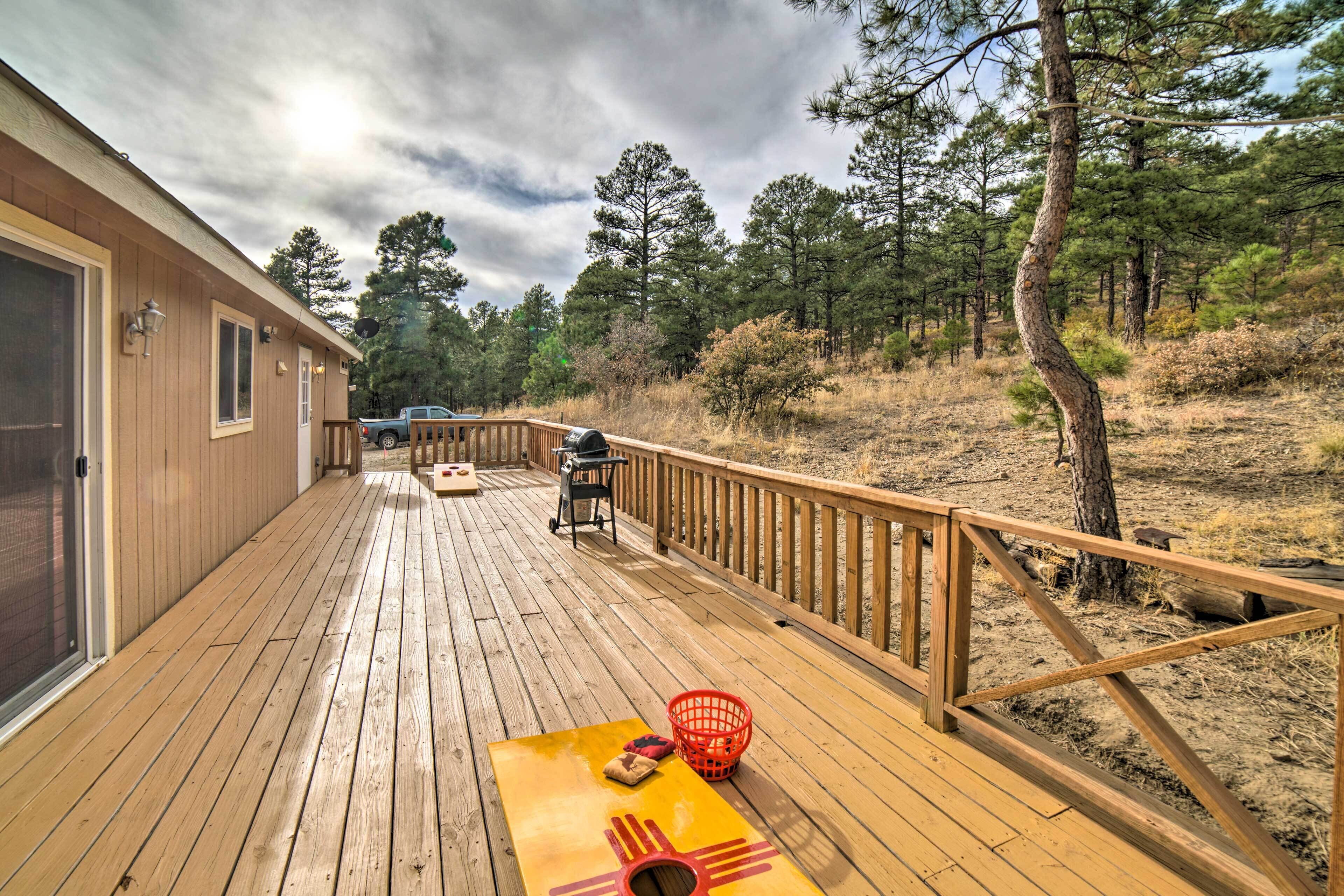 A wooden deck with a picnic table, a barbecue grill, and a red basket.