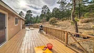 A wooden deck with a picnic table, a barbecue grill, and a red basket.