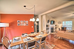 A dining area with a wooden table set for four, surrounded by chairs, and a living area with a sofa and a fireplace.