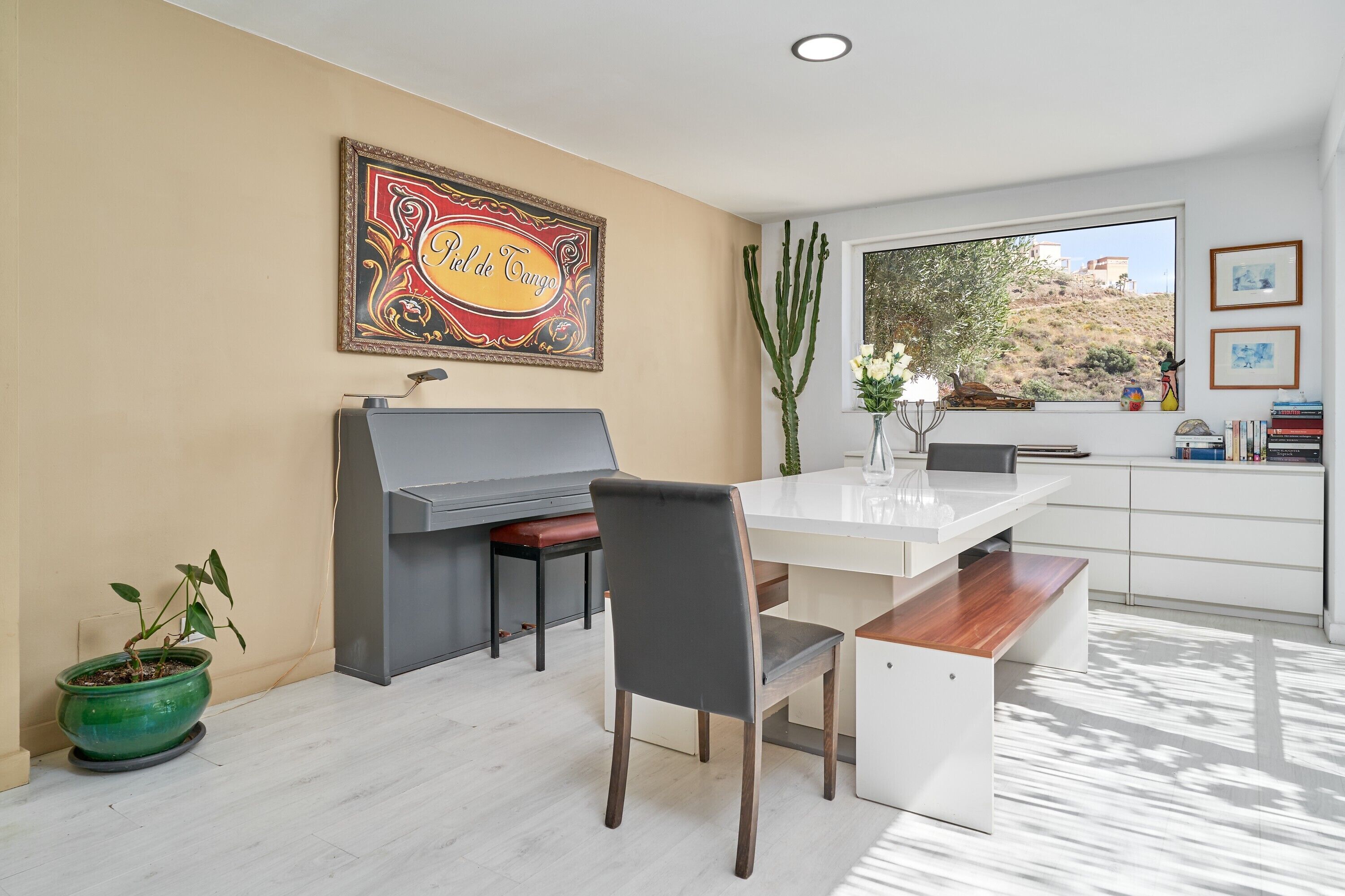 Une cuisine moderne dotée d’un barbecue intégré, d’une table à manger et d’une grande fenêtre offrant une vue sur une colline.
