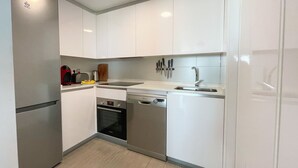 Una cocina moderna con armarios blancos, un refrigerador de acero inoxidable, un lavavajillas y un fregadero.