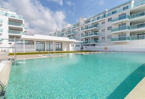 A swimming pool with clear water, surrounded by modern buildings with balconies.