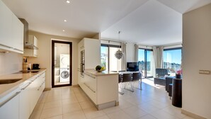 Una cucina moderna con lavatrice integrata, zona pranzo con TV e balcone vista città.