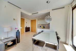 Un espace repas moderne avec une grande table, des chaises, un vase de fleurs et une lampe.
