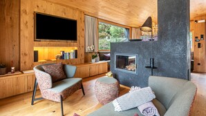 A cozy living room with wooden walls, a fireplace, a flat-screen TV, and comfortable seating.