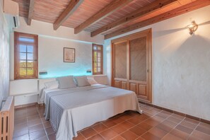A bedroom with a bed, two windows, a ceiling fan, and a wooden wardrobe.
