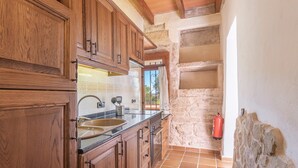 Une cuisine avec des meubles en bois, un évier et un mur en pierre.