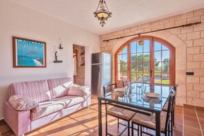 A cozy room with a striped sofa, a glass dining table, and a large window with a view.