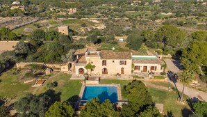 Una amplia villa con piscina, rodeada de exuberante vegetación y un paisaje montañoso.