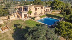 Una villa con piscina, arquitectura de piedra y vistas del paisaje circundante.